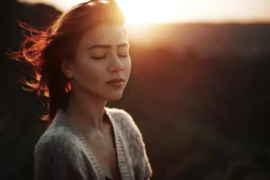 Mujer con los ojos cerrados al atardecer.